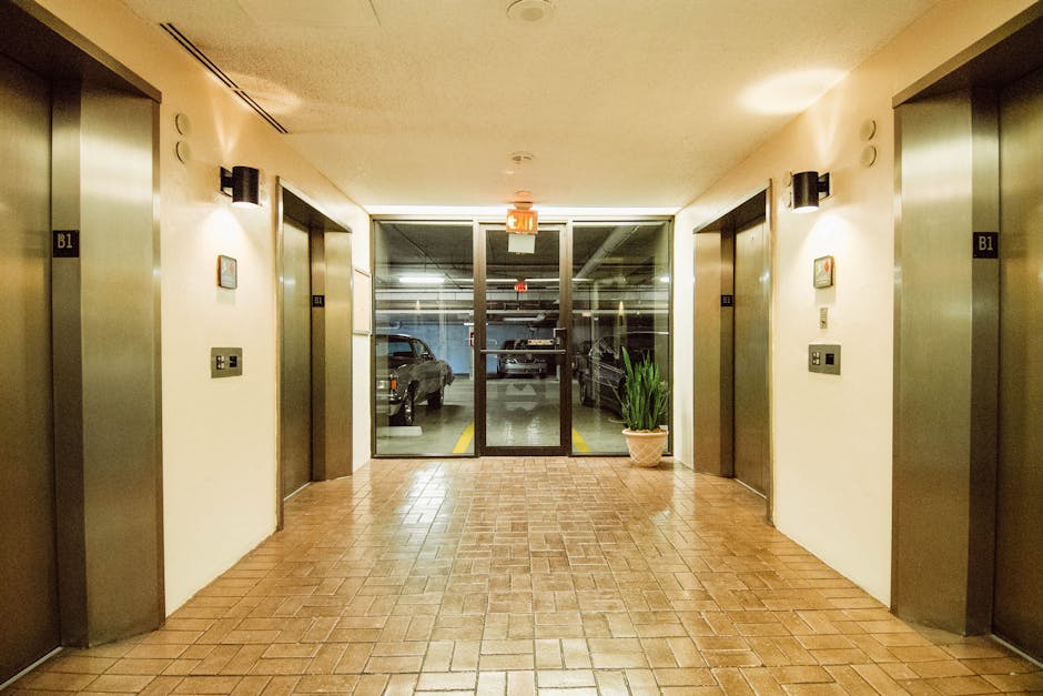 A clean and well-lit parking garage lobby featuring multiple elevators and an exit sign.