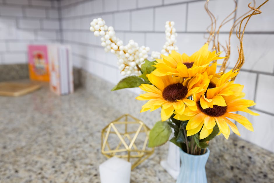 A bouquet of bright yellow sunflowers in a vase displayed on a kitchen countertop with subway tiles.